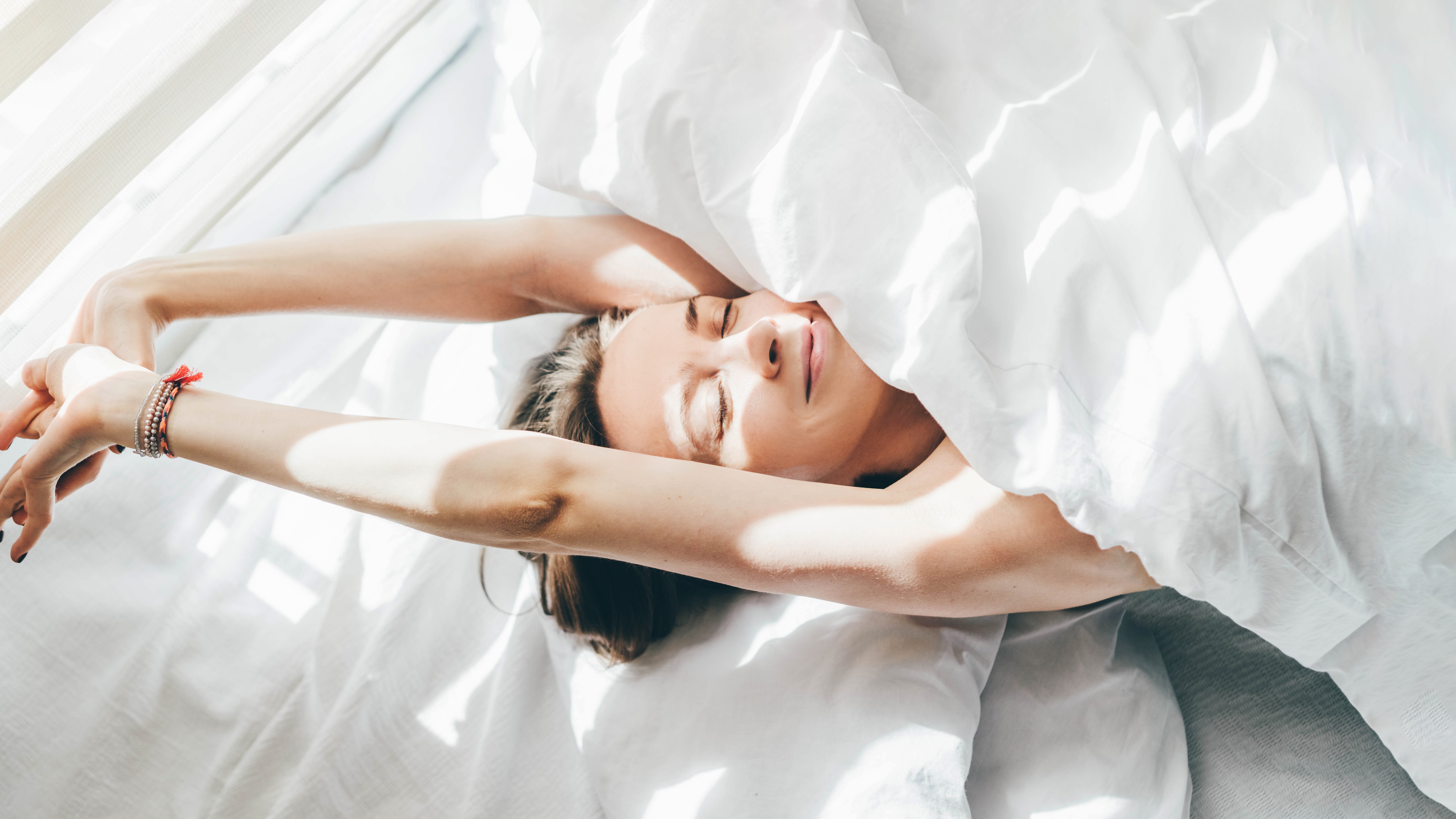 Une photographie d'une femme se réveillant et s'étendant au lit. 