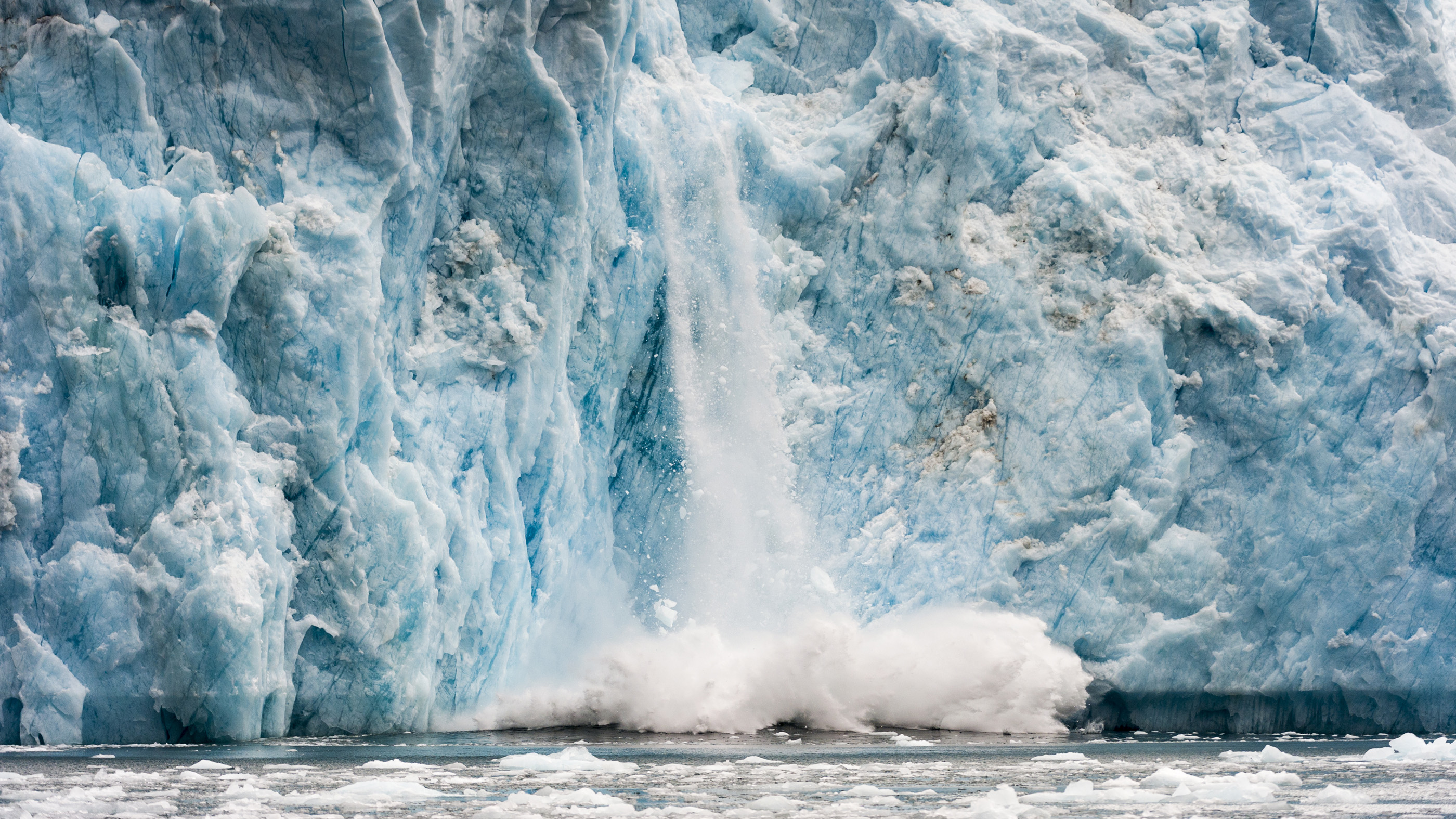 Le vêlage de glace de la zone de fracture d'un glacier s'écrase dans l'océan au Groenland. La fusion d'une telle glace glaciaire mène à la déformation de la croûte de la Terre.