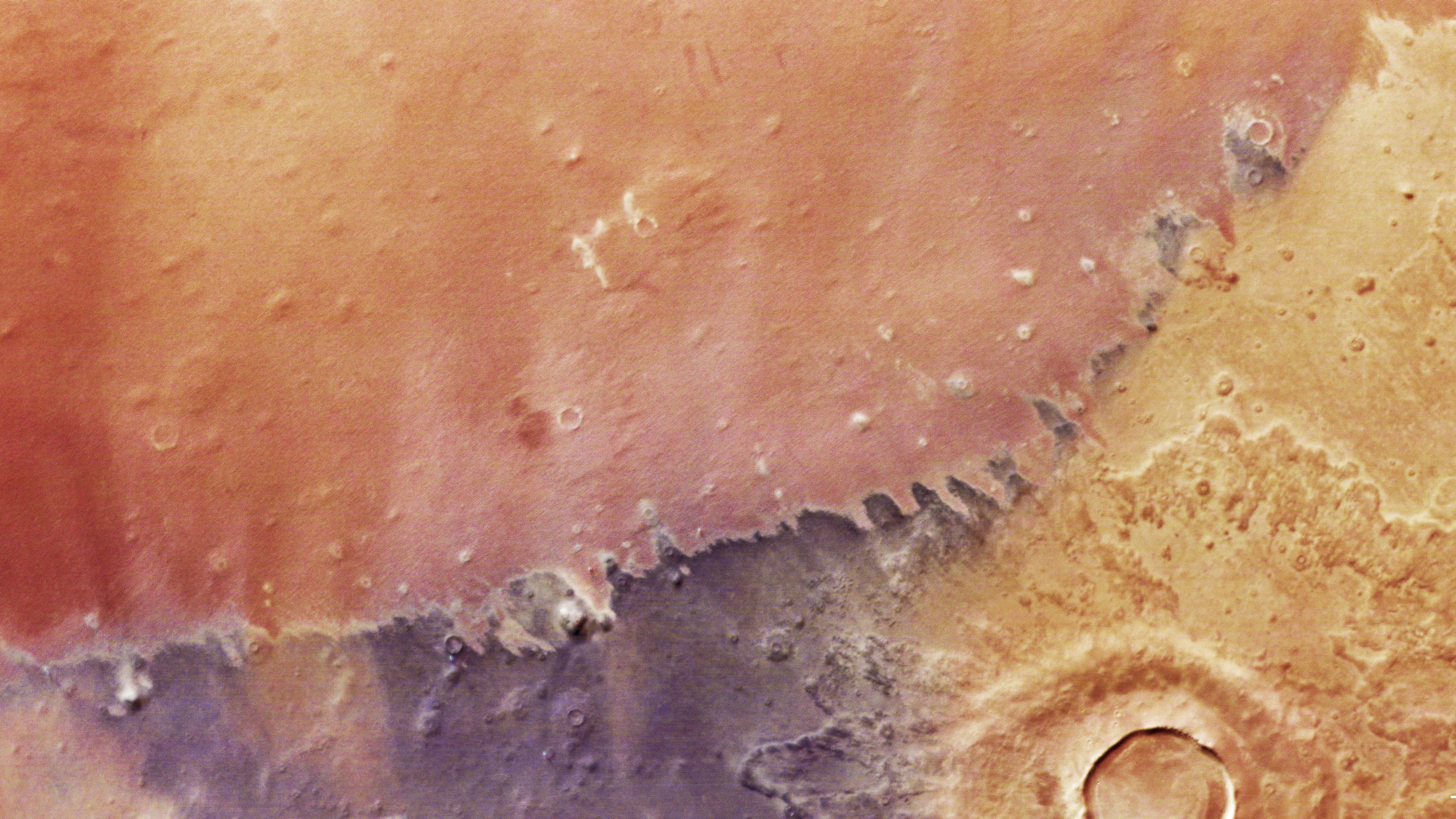 Une image satellite en gros plan de la surface martienne montre des rouges, des oranges et des jaunes.