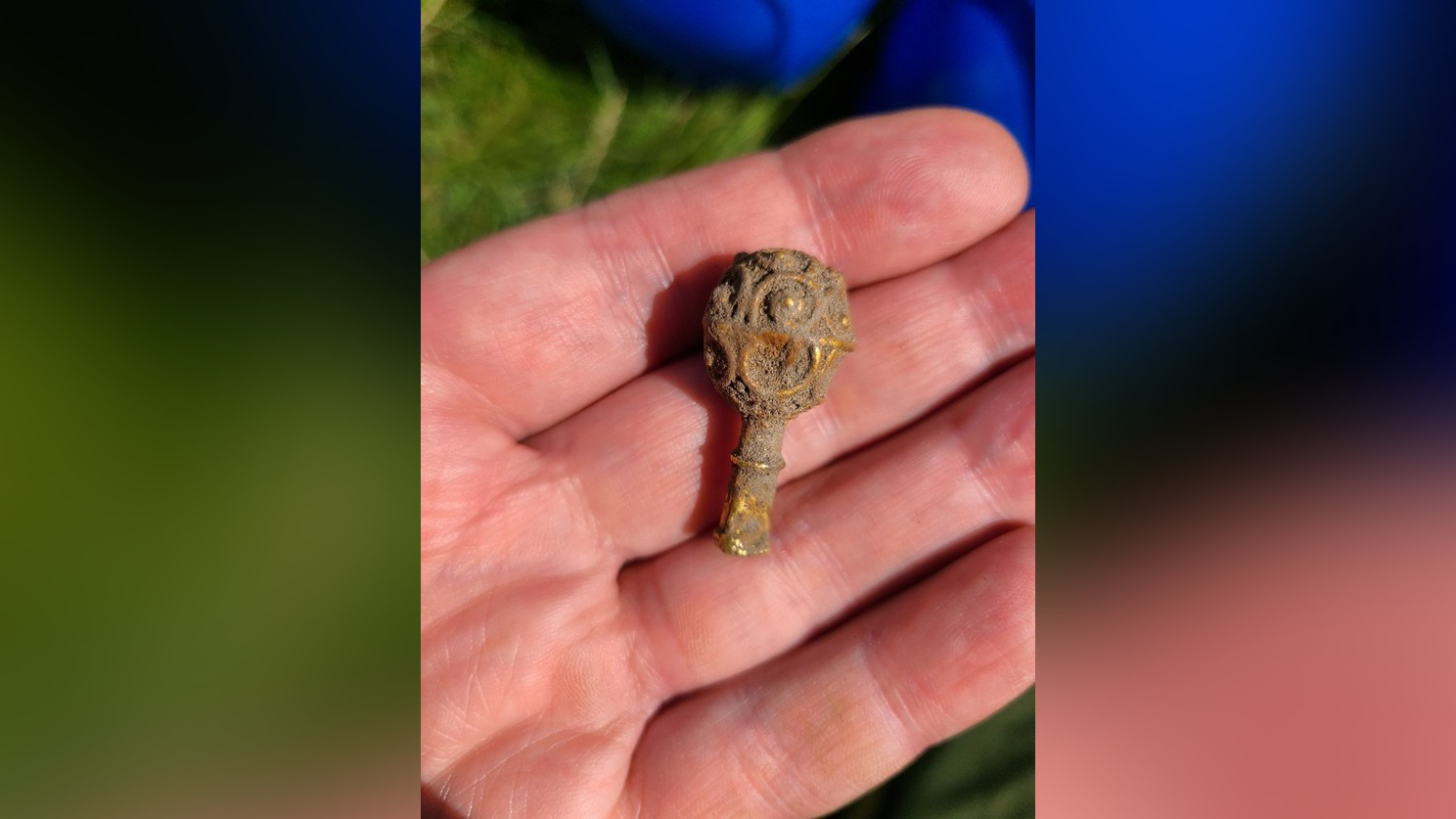 Une personne à la peau claire tient un objet en or sale en forme de petit bouton