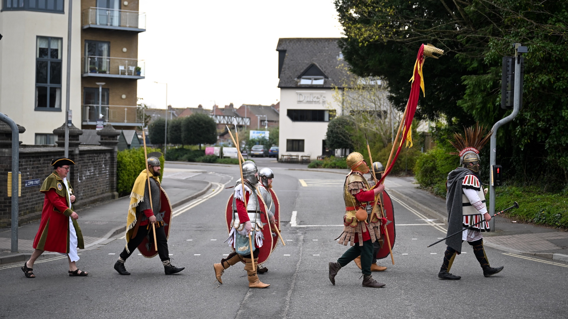 Un groupe de reconstituteurs romains traverse une route dans une recréation de la photo emblématique de l'abbaye des Beatles