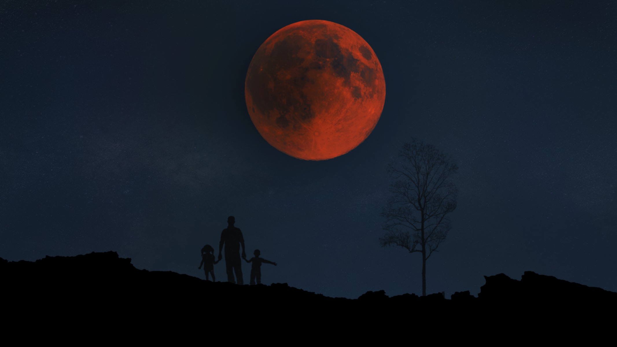 a red blood moon hangs low in the sky during a total lunar eclipse. An adult and two children stand below silhouetted against the dark sky.