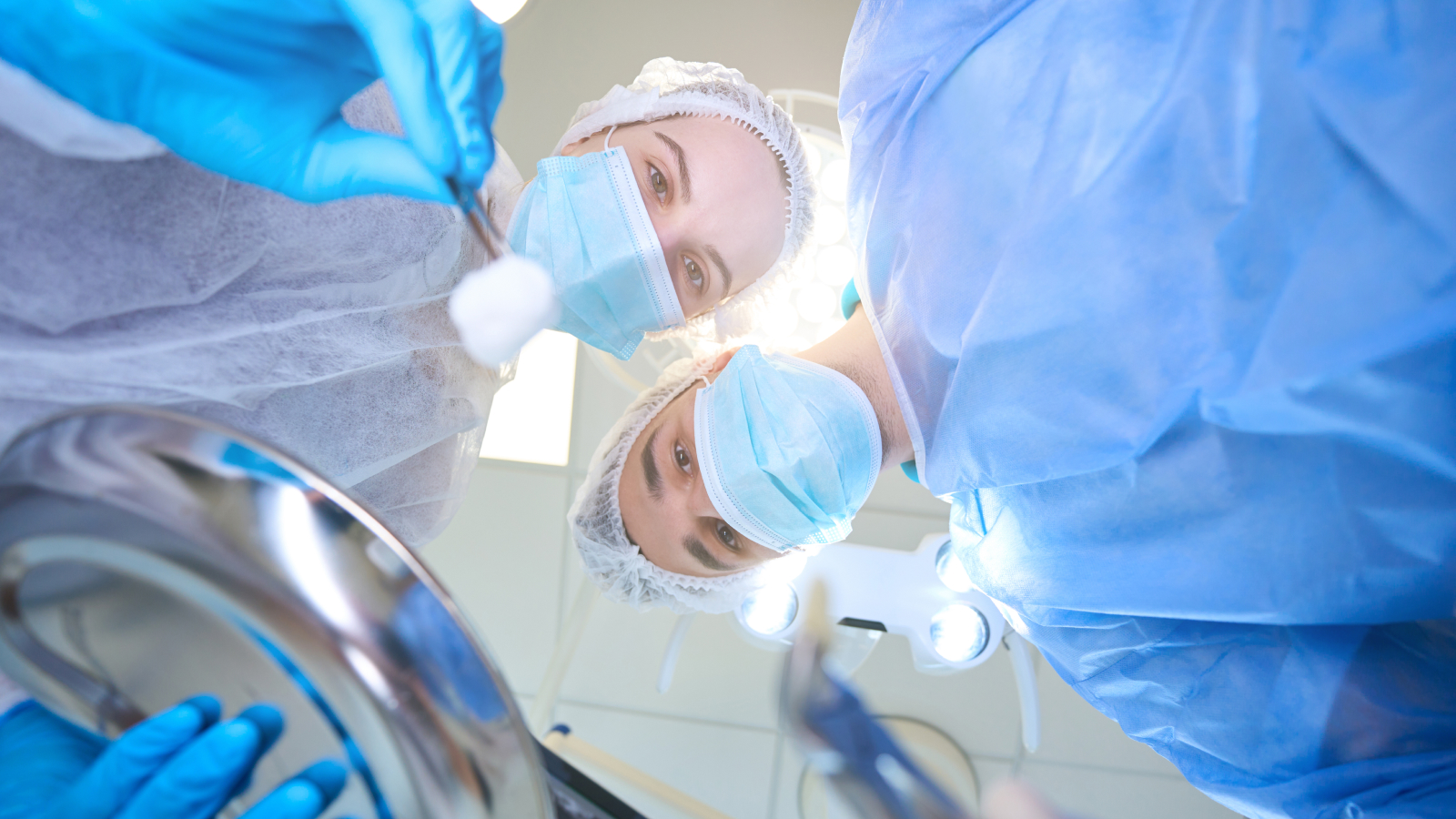 Le jeune chirurgien tient des pinces avec une dent enlevée, un assistant a une pince à épiler avec un écouvillon dans ses mains. Stock Image de la chirurgie dentaire, angle de la caméra en point de vue du patient.