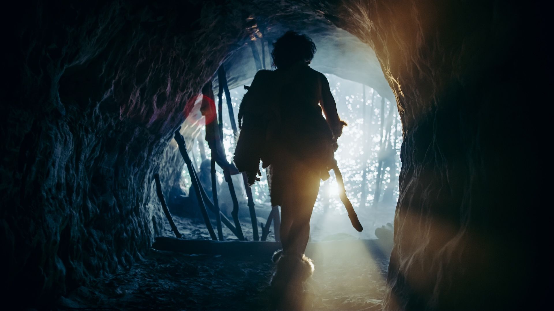 A recreation photograph of a Neanderthal man coming out of a cave