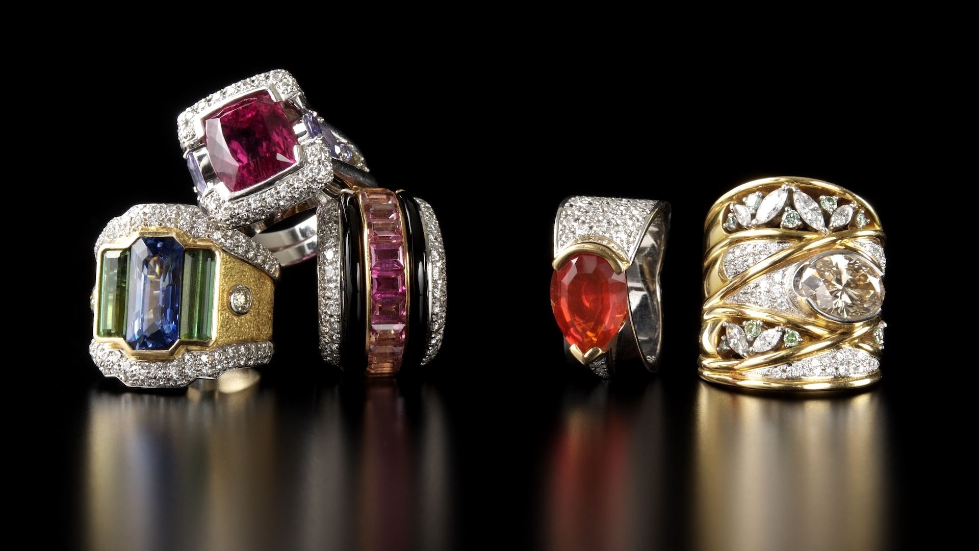 a collection of large gemstone rings on a black background