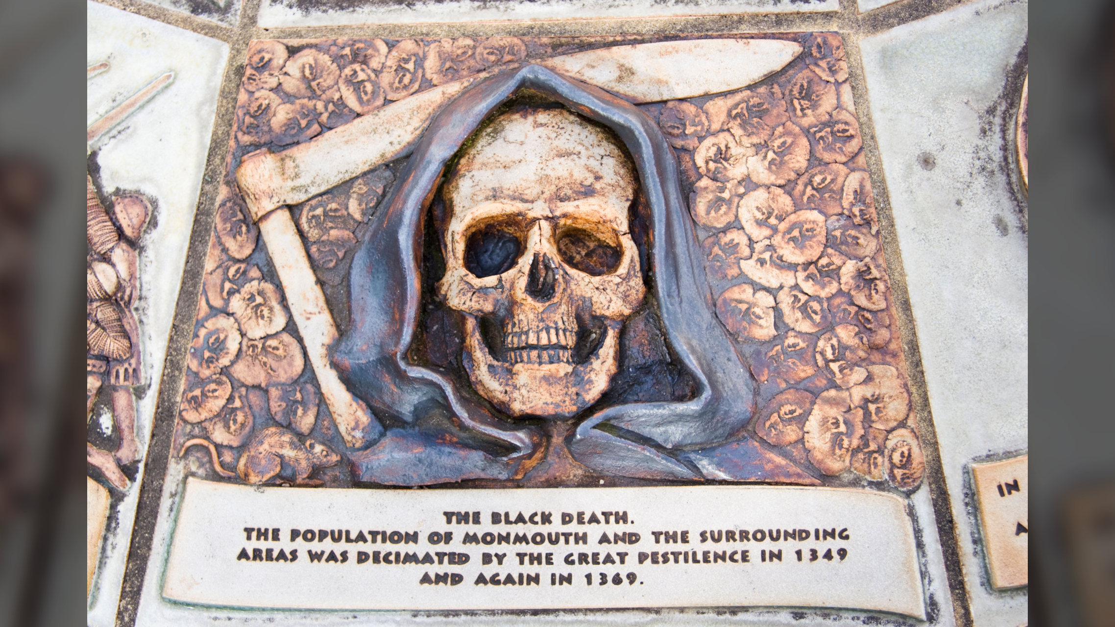 une plaque avec un crâne humain habillé en faucheuse avec un texte qui dit 