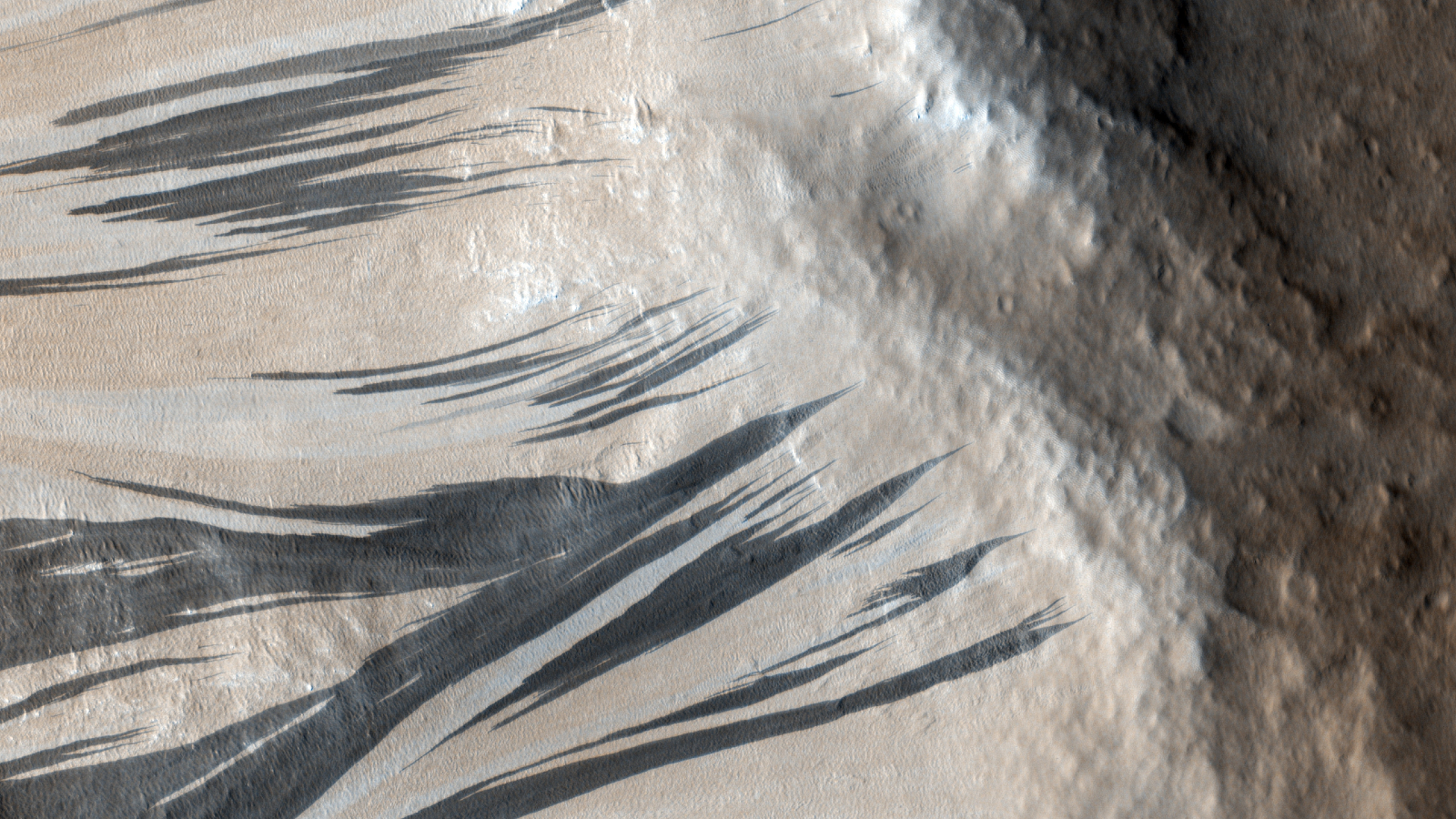 Une photo aérienne de grandes stries noires s'écoulant sur les pentes d'une pente sur Mars