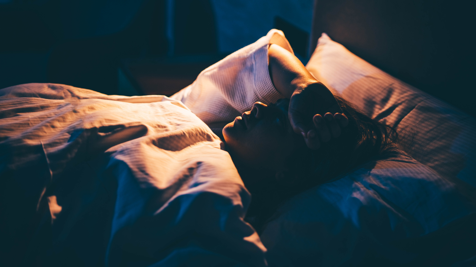 Femme souffrant d'insomnie. Jeune femme allongée sur le lit avec la main sur le front.