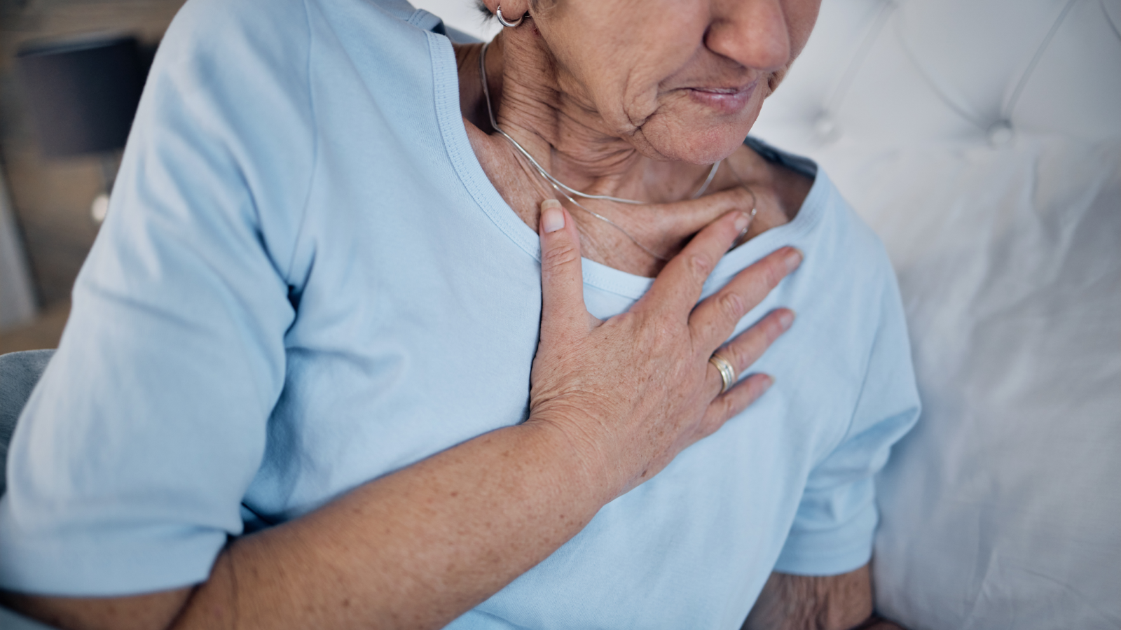 Vieille femme au lit et douleurs thoraciques le matin, inconfort et urgence en cas de maladie. Femme médicale, mature et dame âgée dans la chambre, crise cardiaque et crise de panique avec la main touchant le corps.