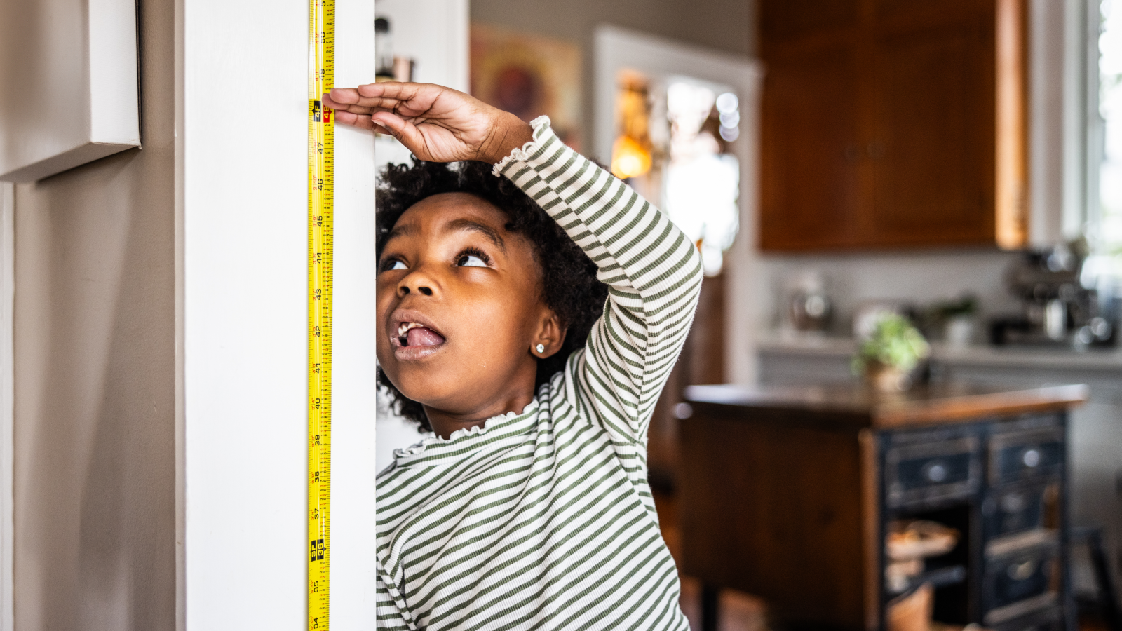 Young girl checking her height on the wall