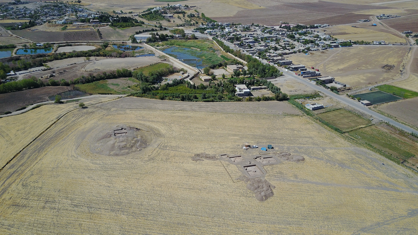 Birds-eye-view of the Gird-î Kazhaw archaeological site near a modern town.