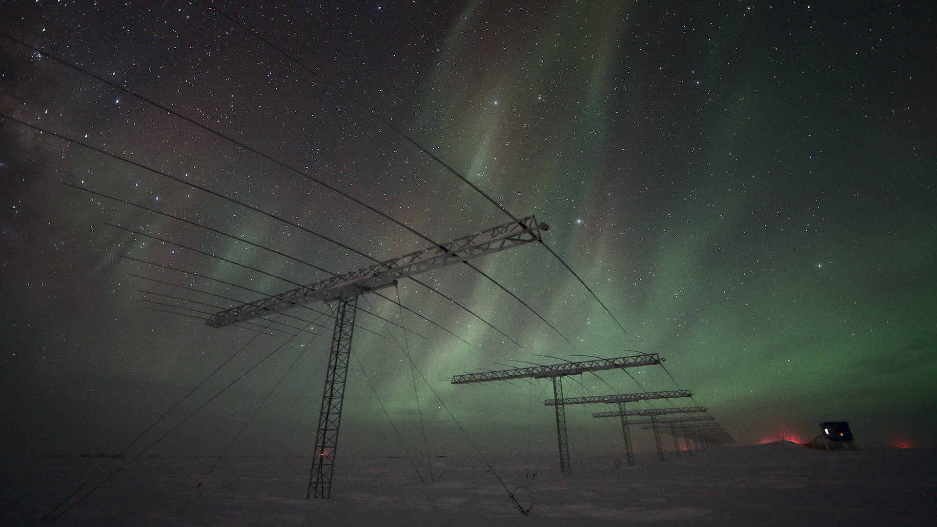 Une photo d'aurores au-dessus du pôle Sud avec des antennes et des fils électriques visibles