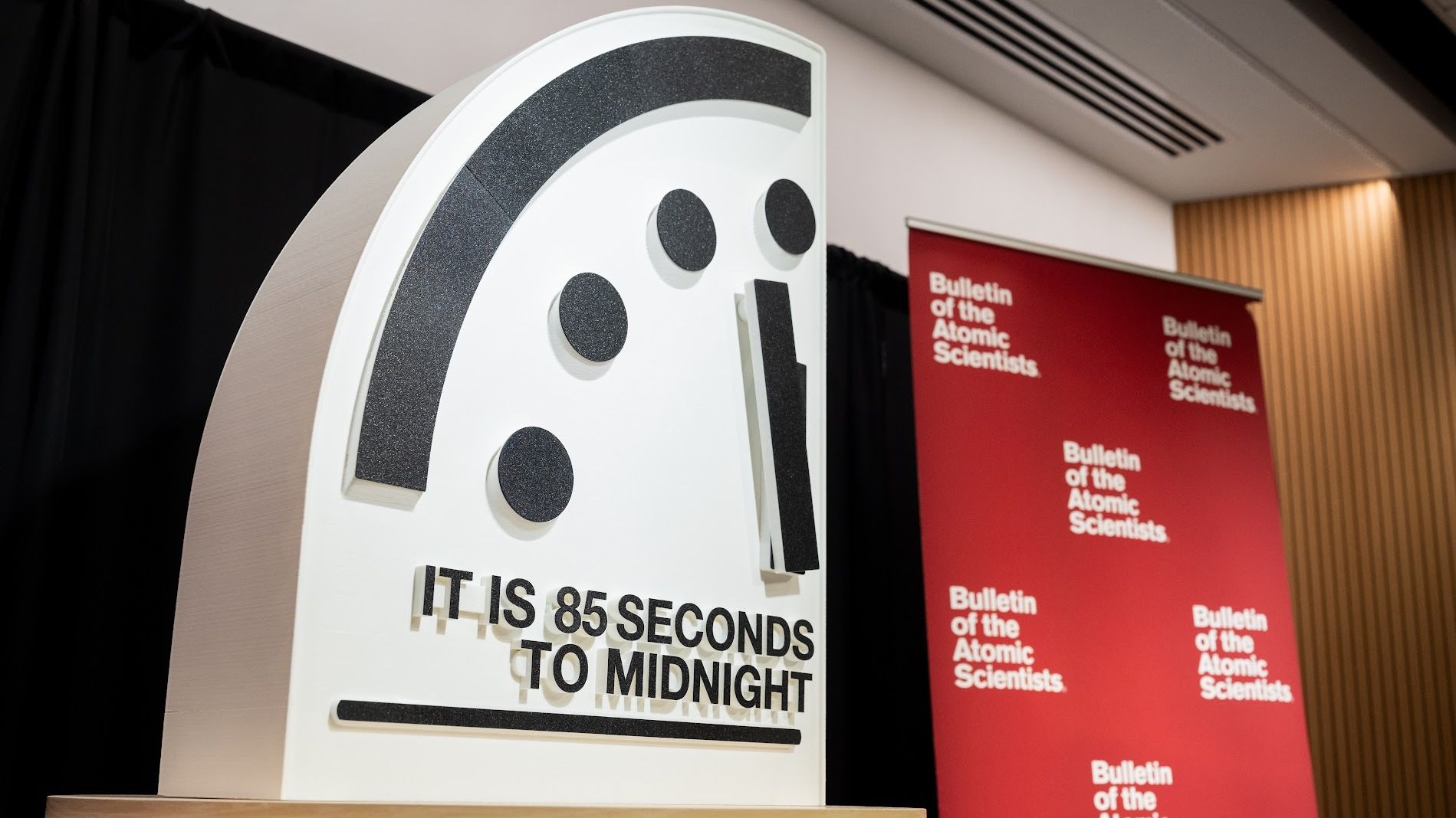 A presentation showing part of a clock at 85 seconds to midnight next to a red banner of the Bulletin of the Atomic Scientists.