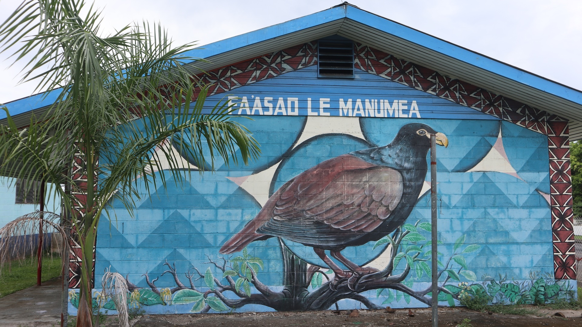 Photo de l'extérieur d'un bâtiment sur lequel se trouve une fresque murale représentant un grand oiseau vu de côté. Au-dessus de l'oiseau, il est écrit 