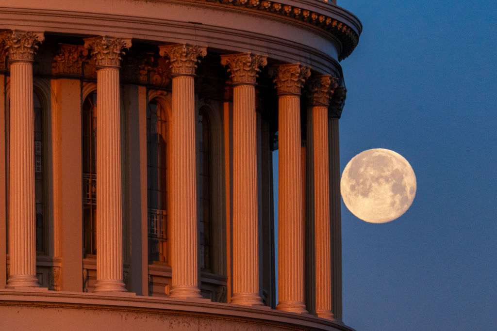 Photo de la pleine lune derrière les piliers du Capitole des États-Unis le 25 février 2024, à Washington, DC.