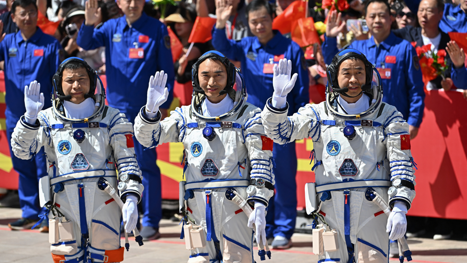 Une photo de trois astronautes chinois saluant les caméras avant de se lancer dans l'espace