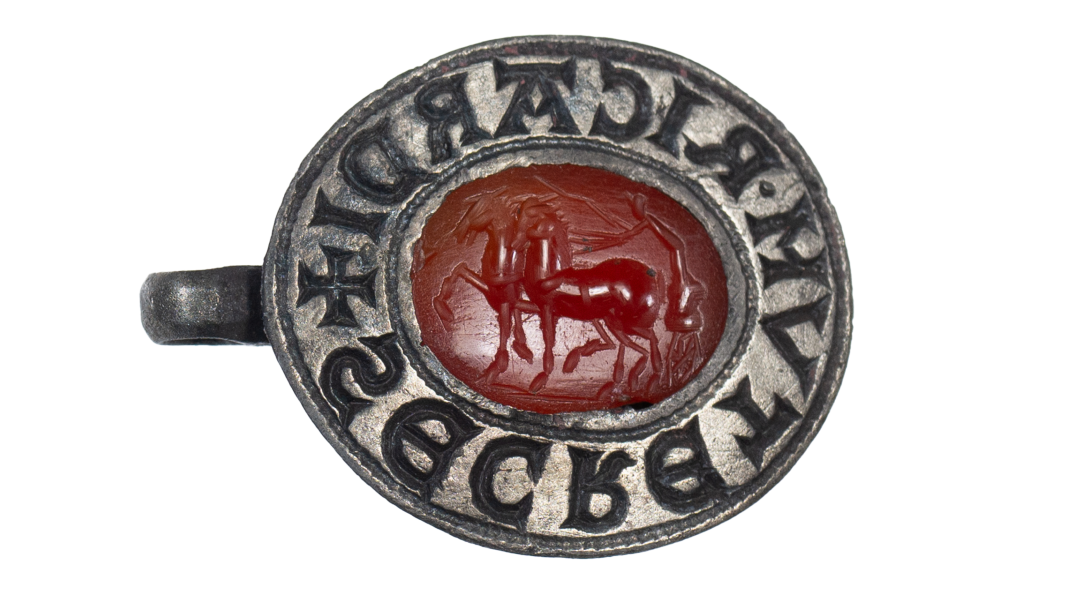 a metal seal with red intaglio gem carved like an ancient chariot