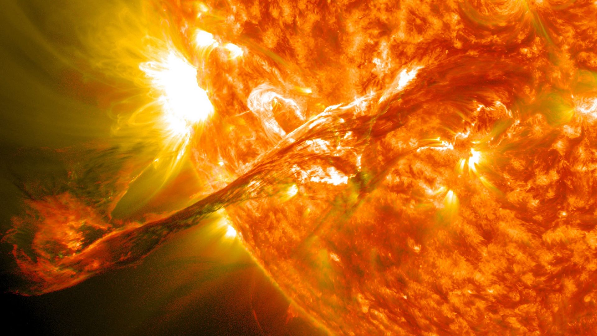 An illustration of a close up on our sun, with the golden ball of orange gas ejecting material to the bottom left of the image.