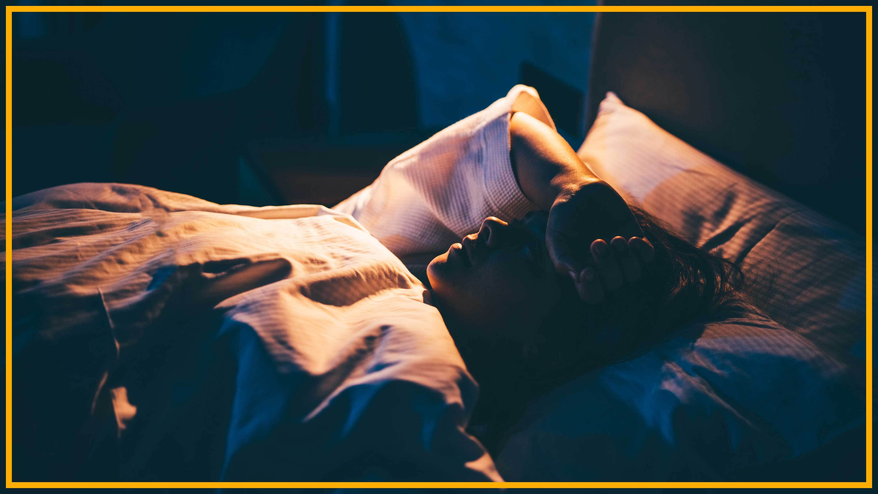 photo d'une femme allongée dans son lit avec un bras posé sur son front