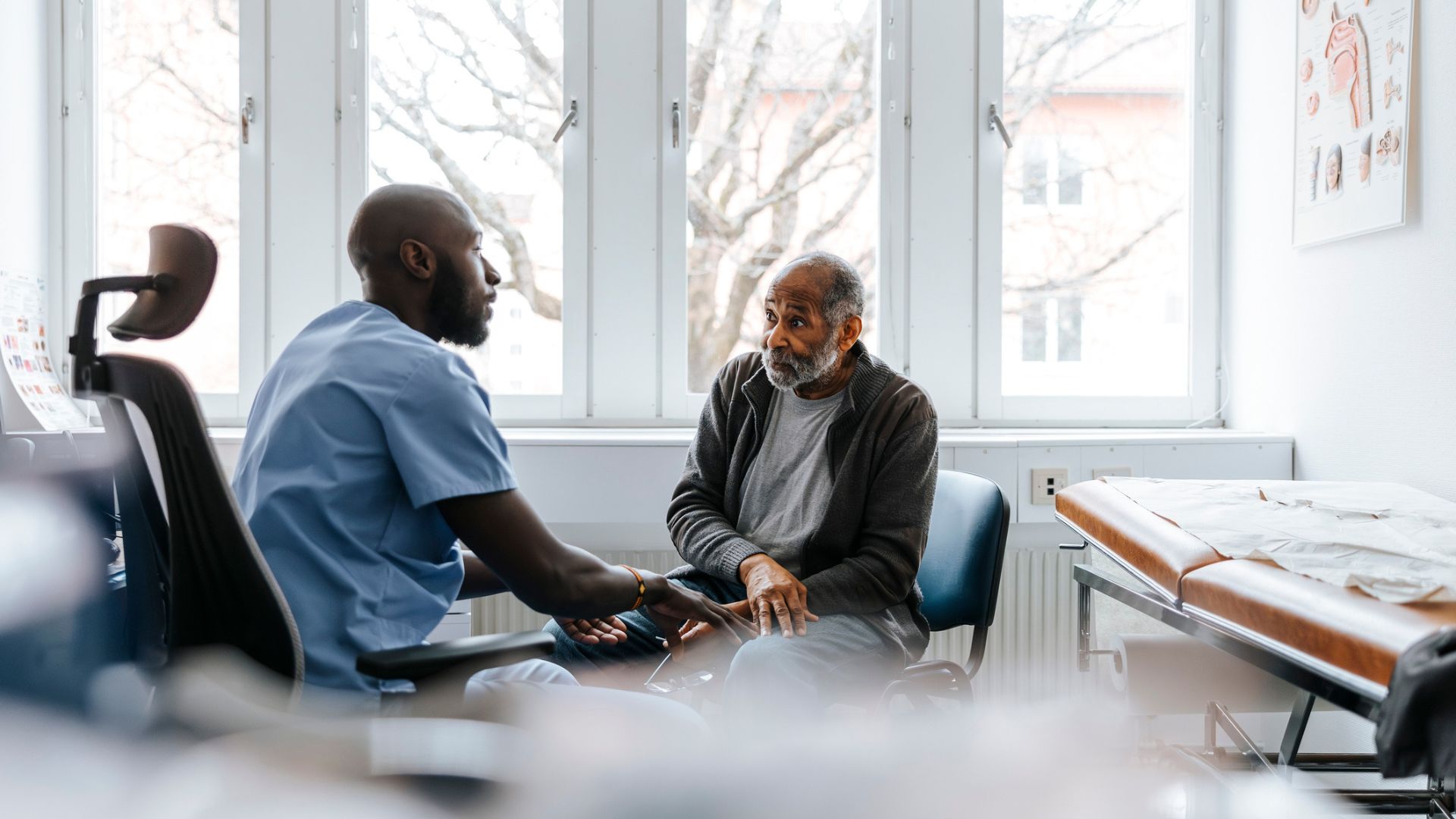 Photo d'un professionnel de la santé discutant avec un patient âgé. 