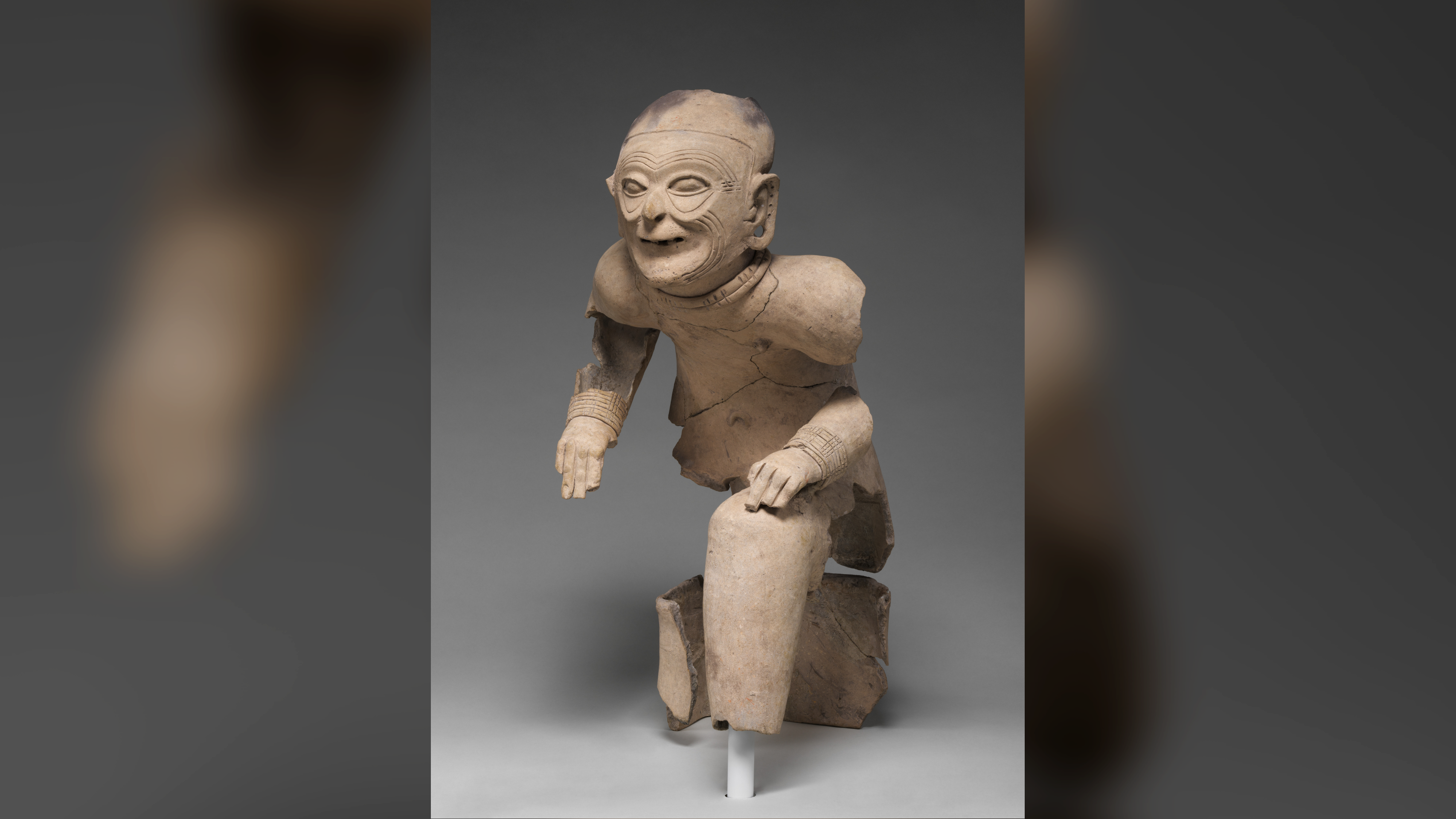 une figurine en céramique cassée représentant un homme âgé assis sur un tabouret