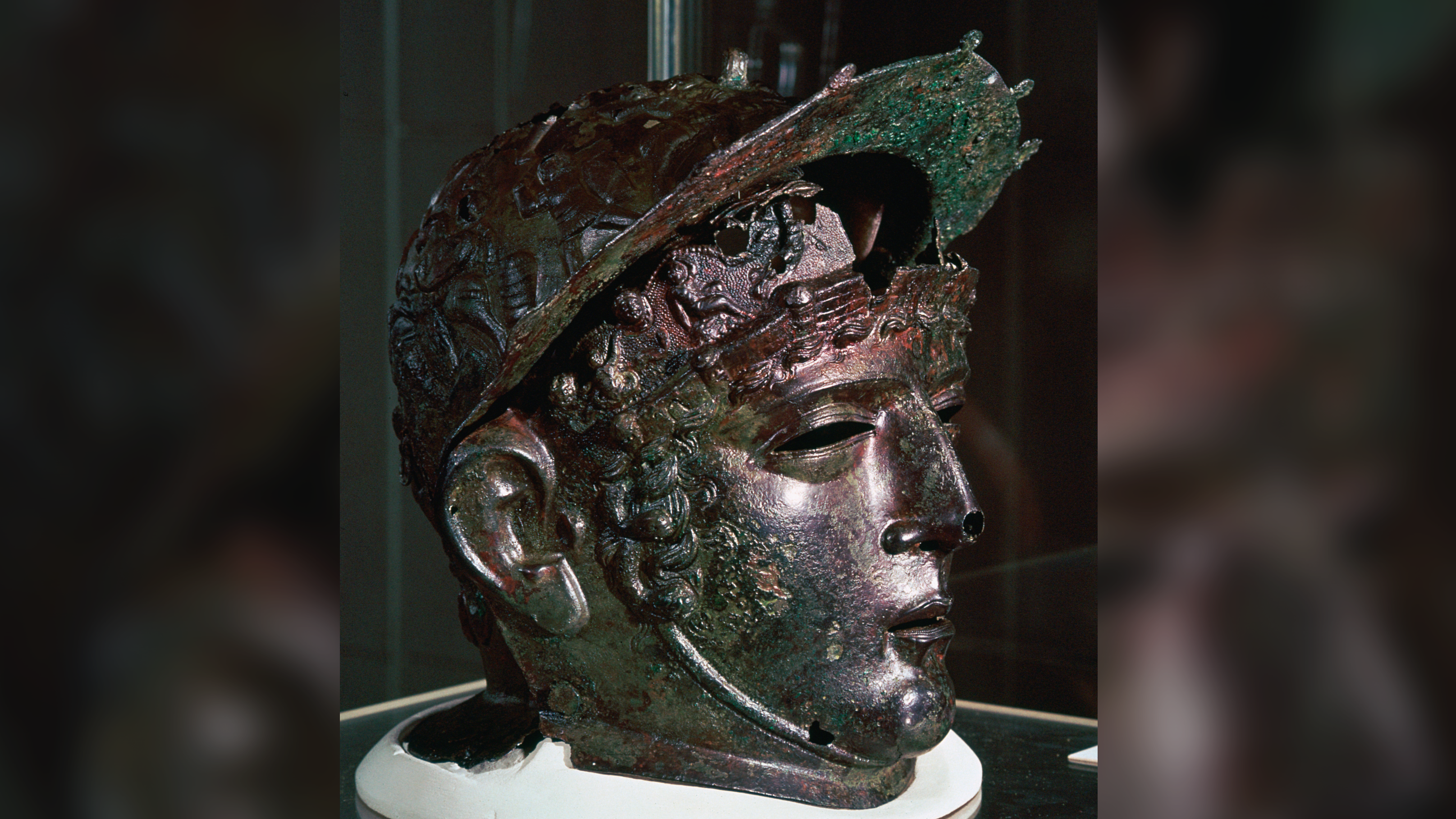 un casque en bronze verdâtre en forme de tête et de visage d'homme
