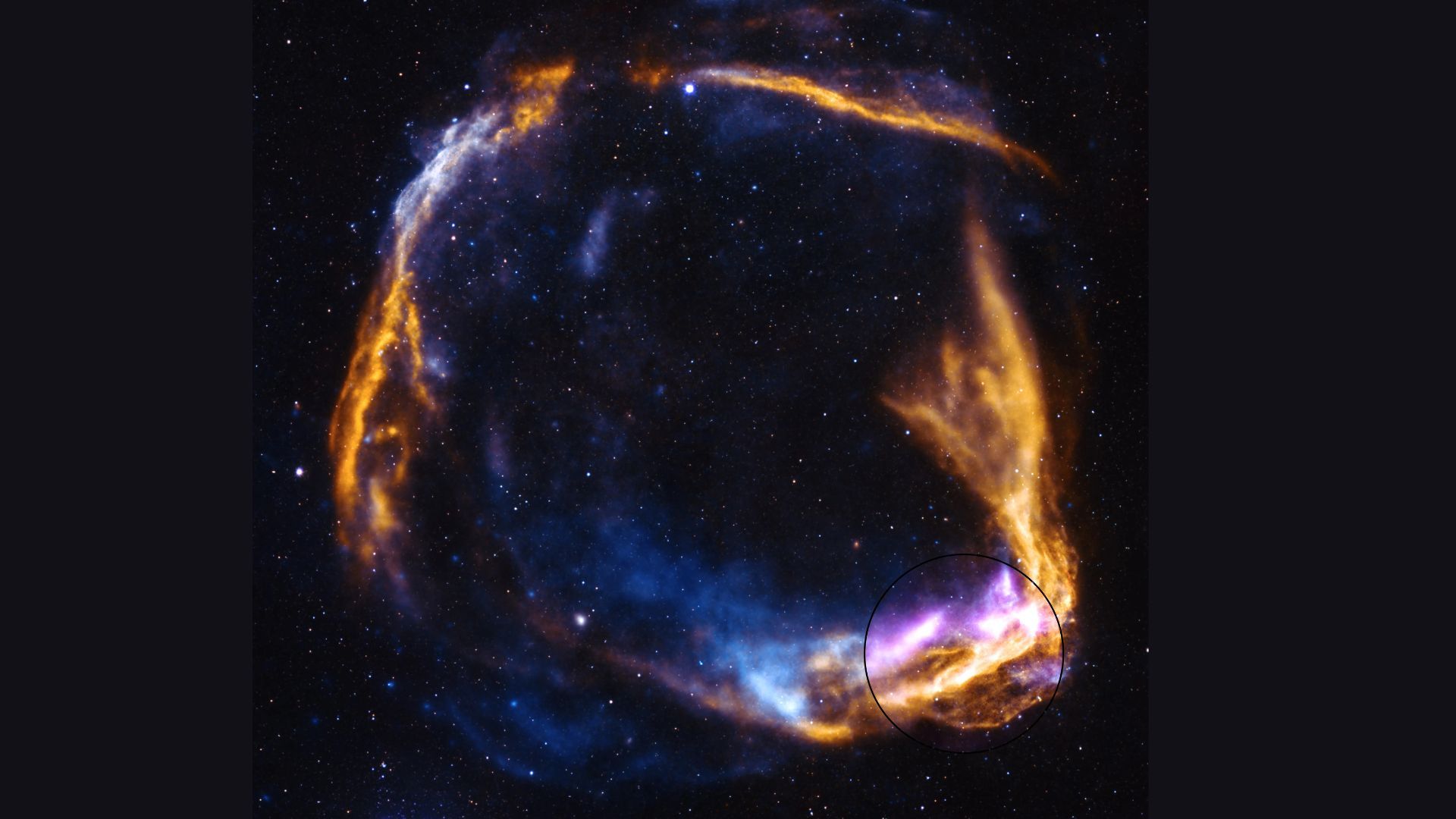 A circular array of blue and pink and orange gas swirls against a dark starry background