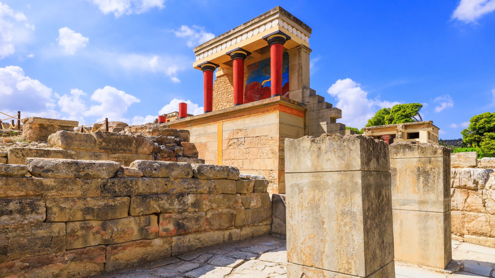 An illustration of a stone temple next to crumbling brick walls. The pillars on the temple are bright scarlet red with a light tan roof above
