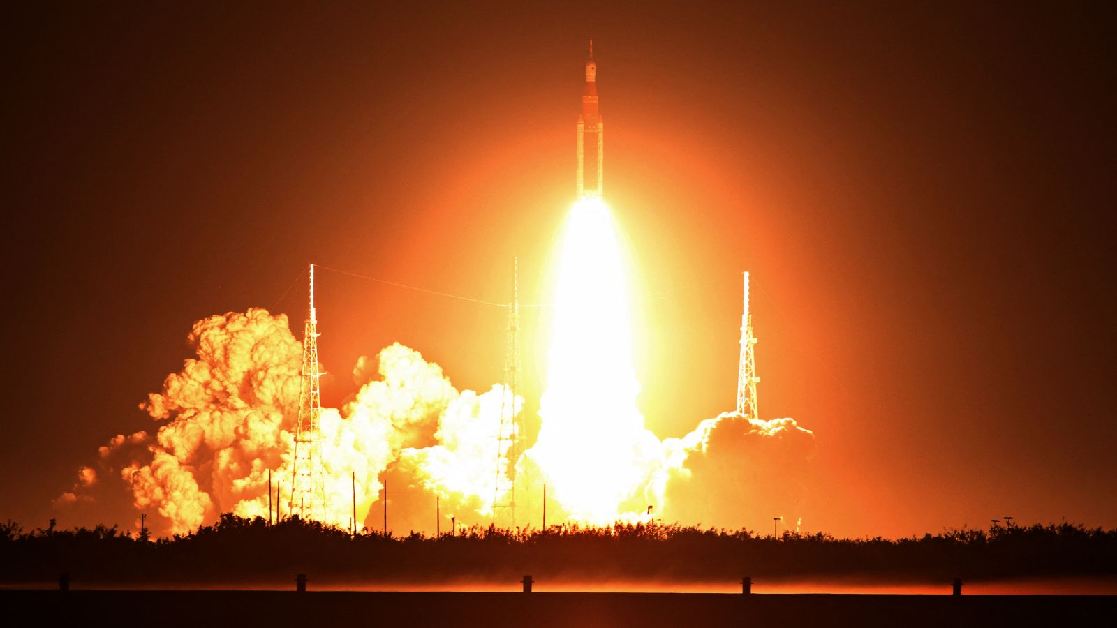 Photo of a stream of orange fire coming from the Artemis I rocket as it launched into space at night