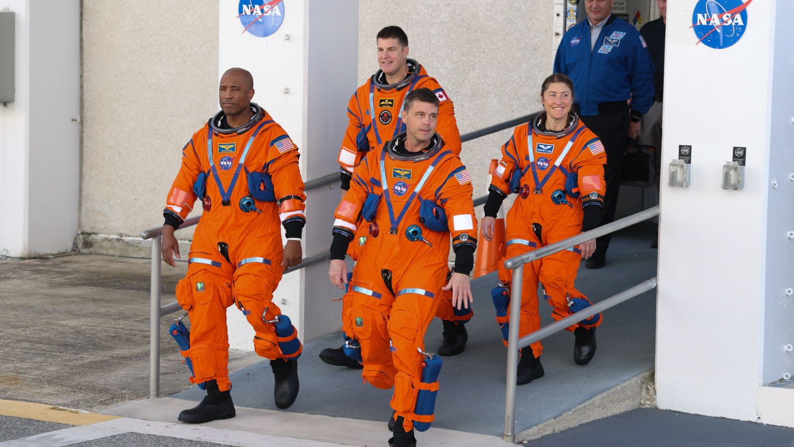 Les quatre astronautes d'Artemis II descendant une rampe dans leurs combinaisons de vol orange