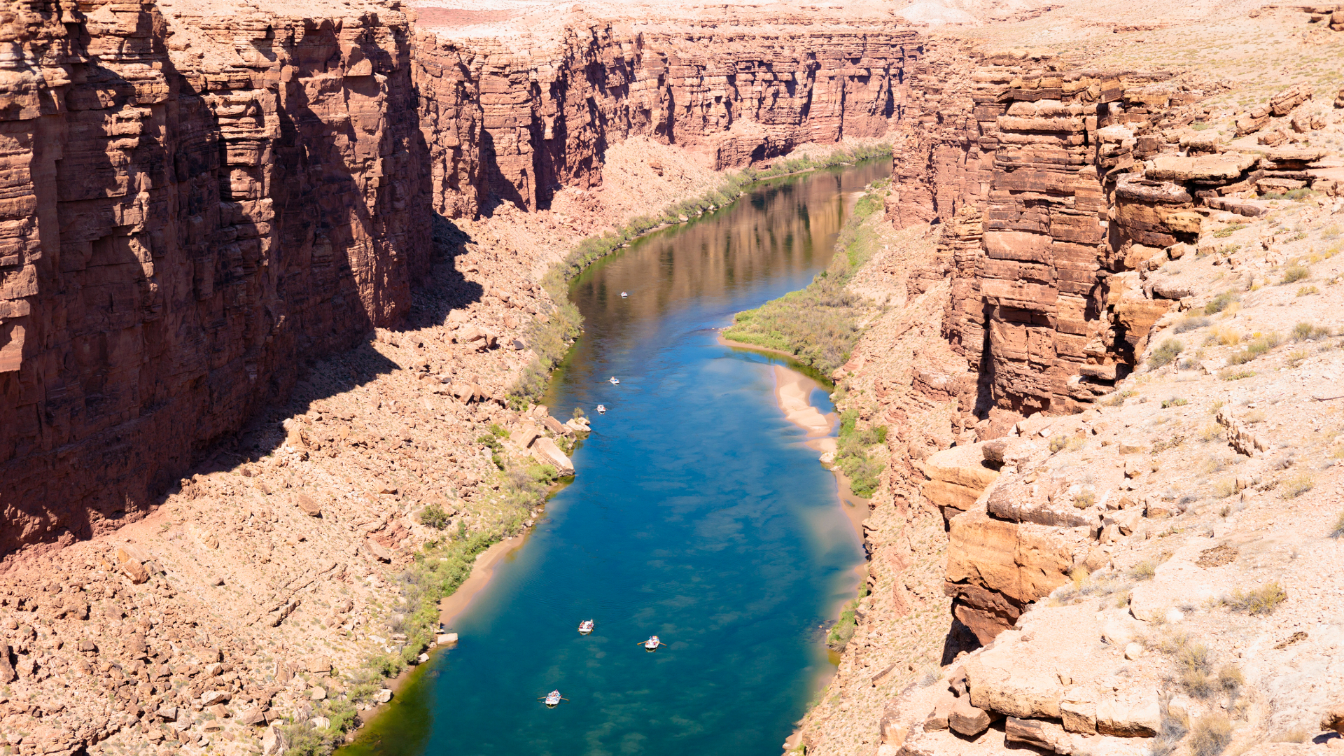 Une vue plongeante sur une rivière bleue serpentant à travers une vallée rocheuse. 