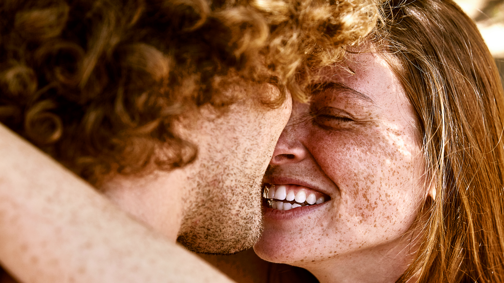 two redheaded people - a man and a woman - hugging and looking at one another