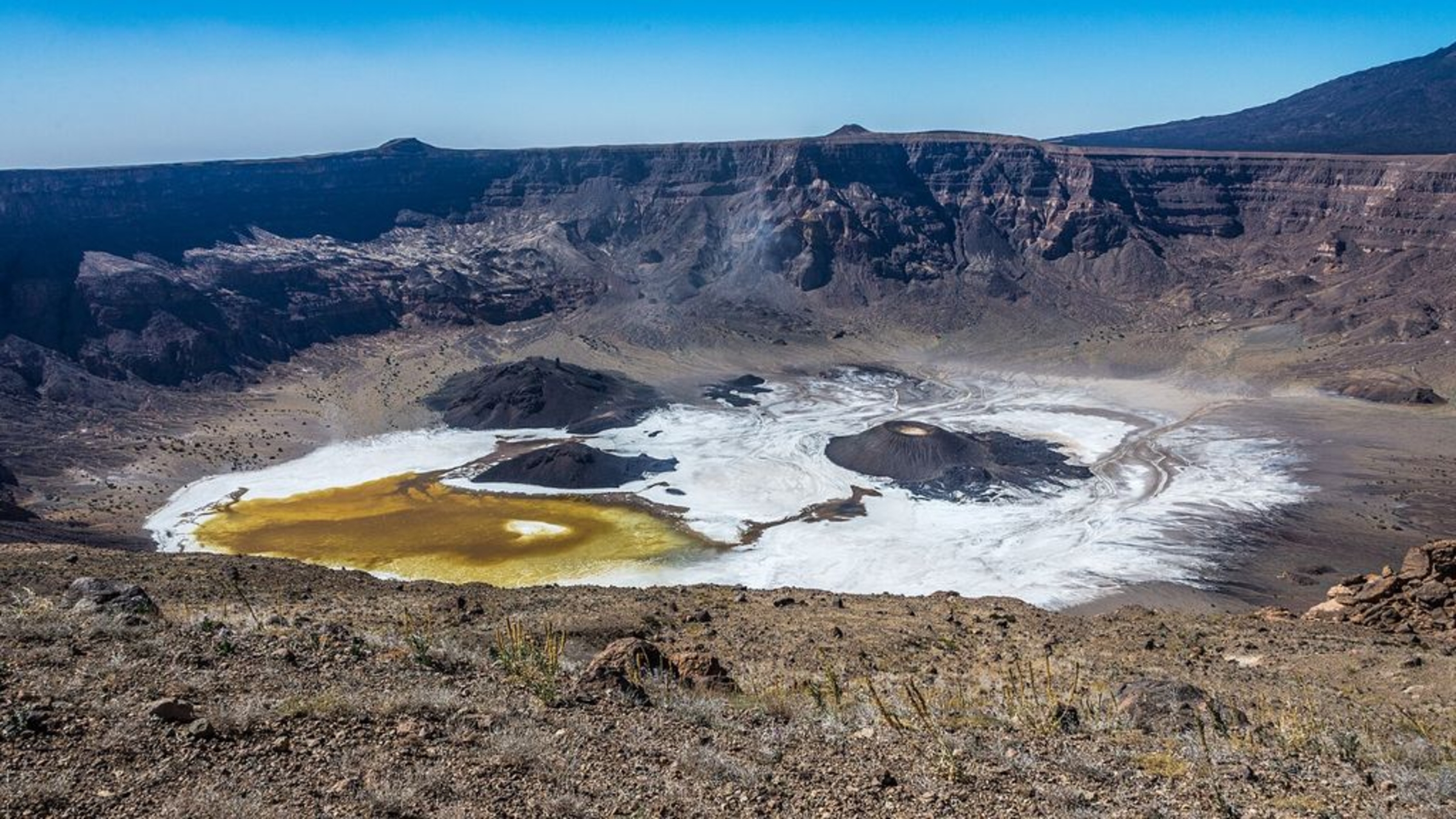 Une photo de la caldeira de Trou au Natron prise depuis le bord du cratère, montrant son sol blanc salé