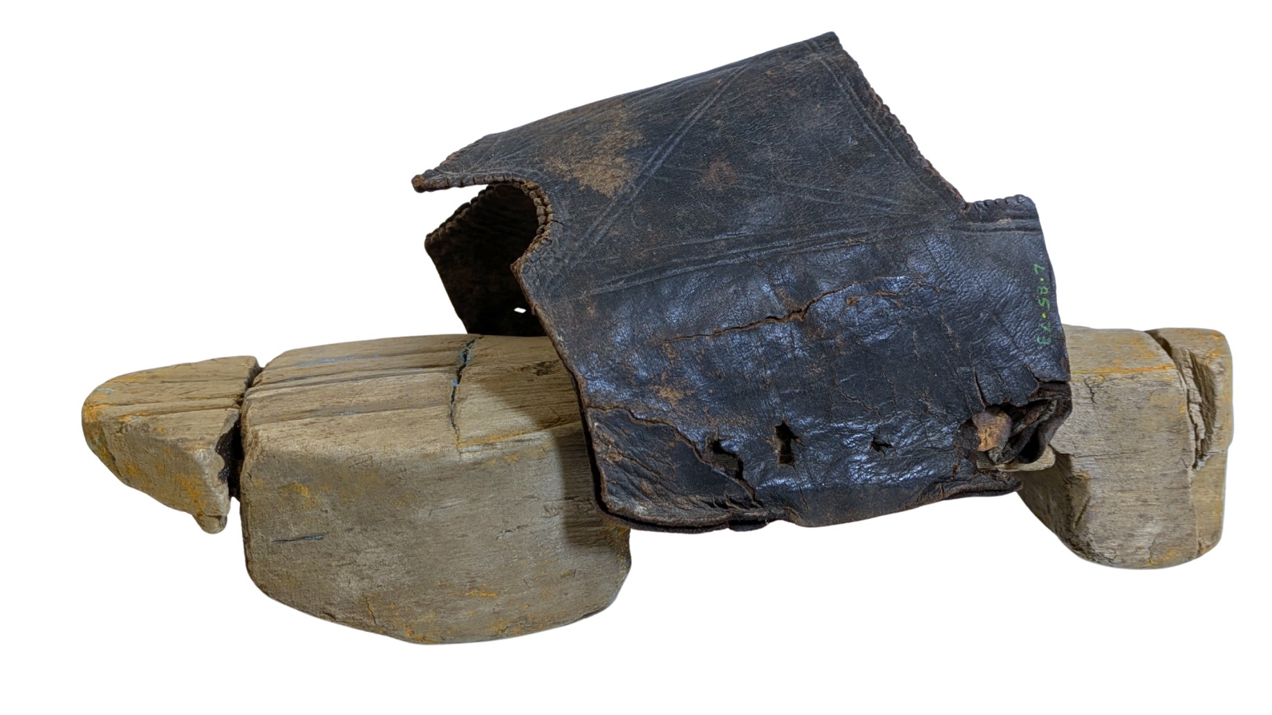 Un talon de chaussure en bois est vu attaché à une lanière en cuir sur un fond blanc