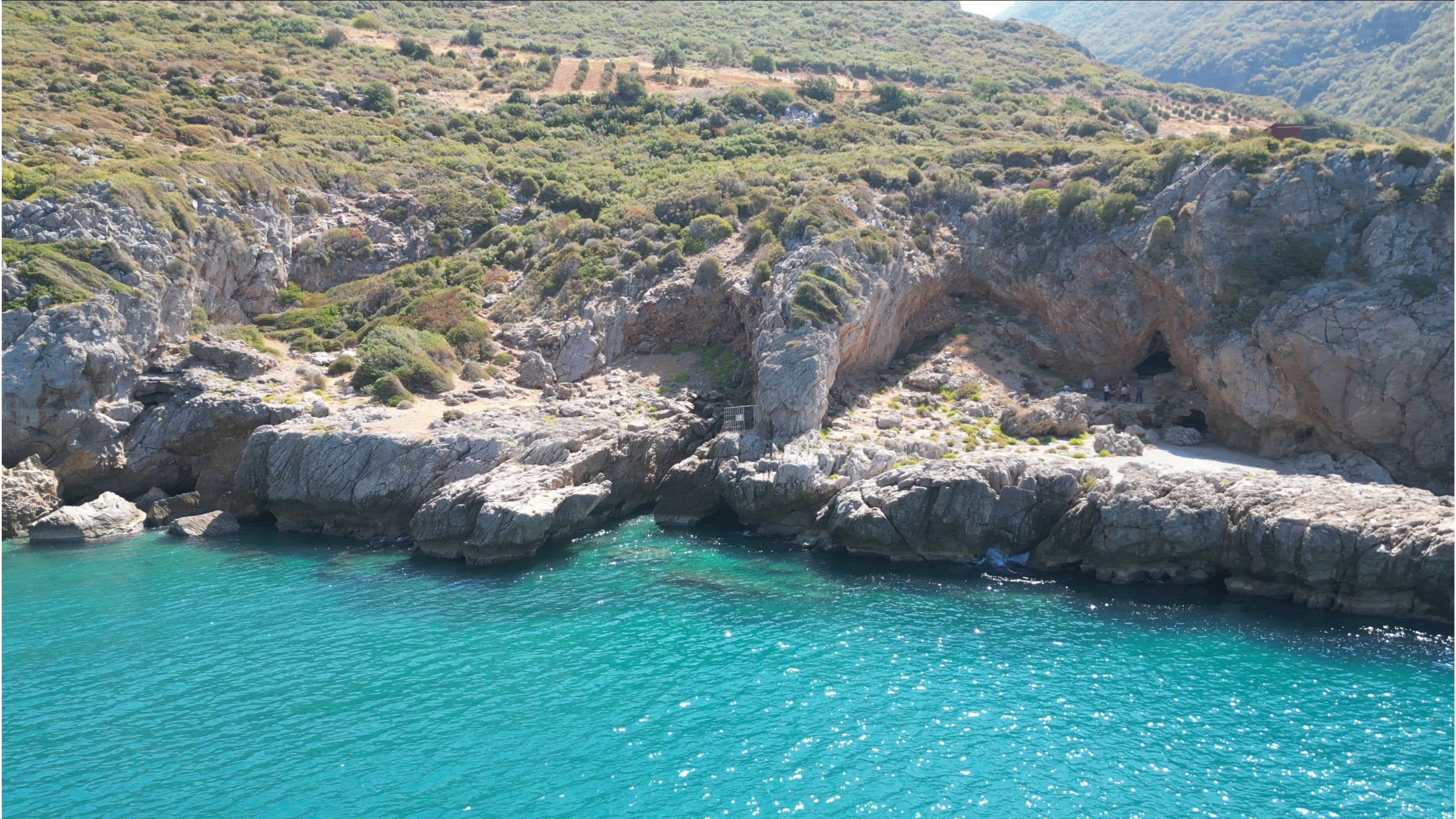 Eaux turquoise entourant l'entrée rocheuse d'une grotte en Turquie.