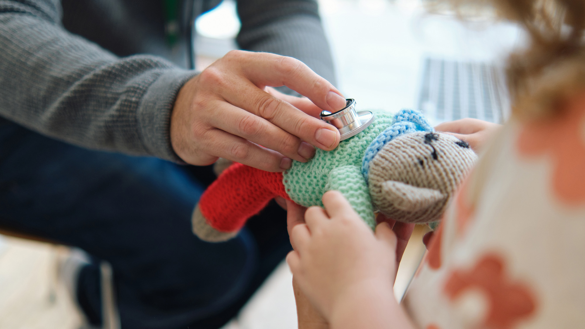 Une personne met un stéthoscope sur un jouet en peluche
