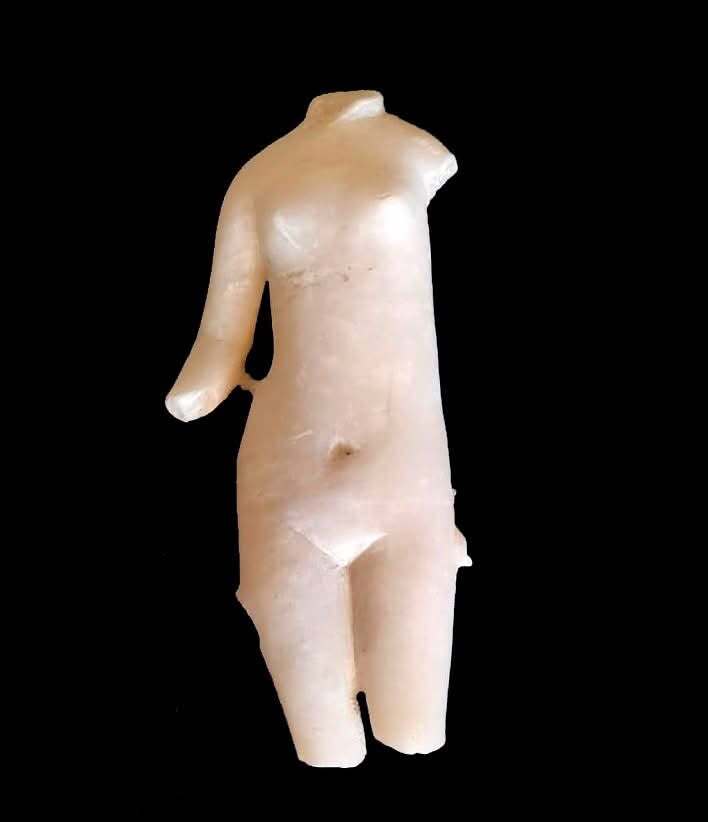 Une petite statue en marbre blanc avec un bras se dresse sur un fond noir.