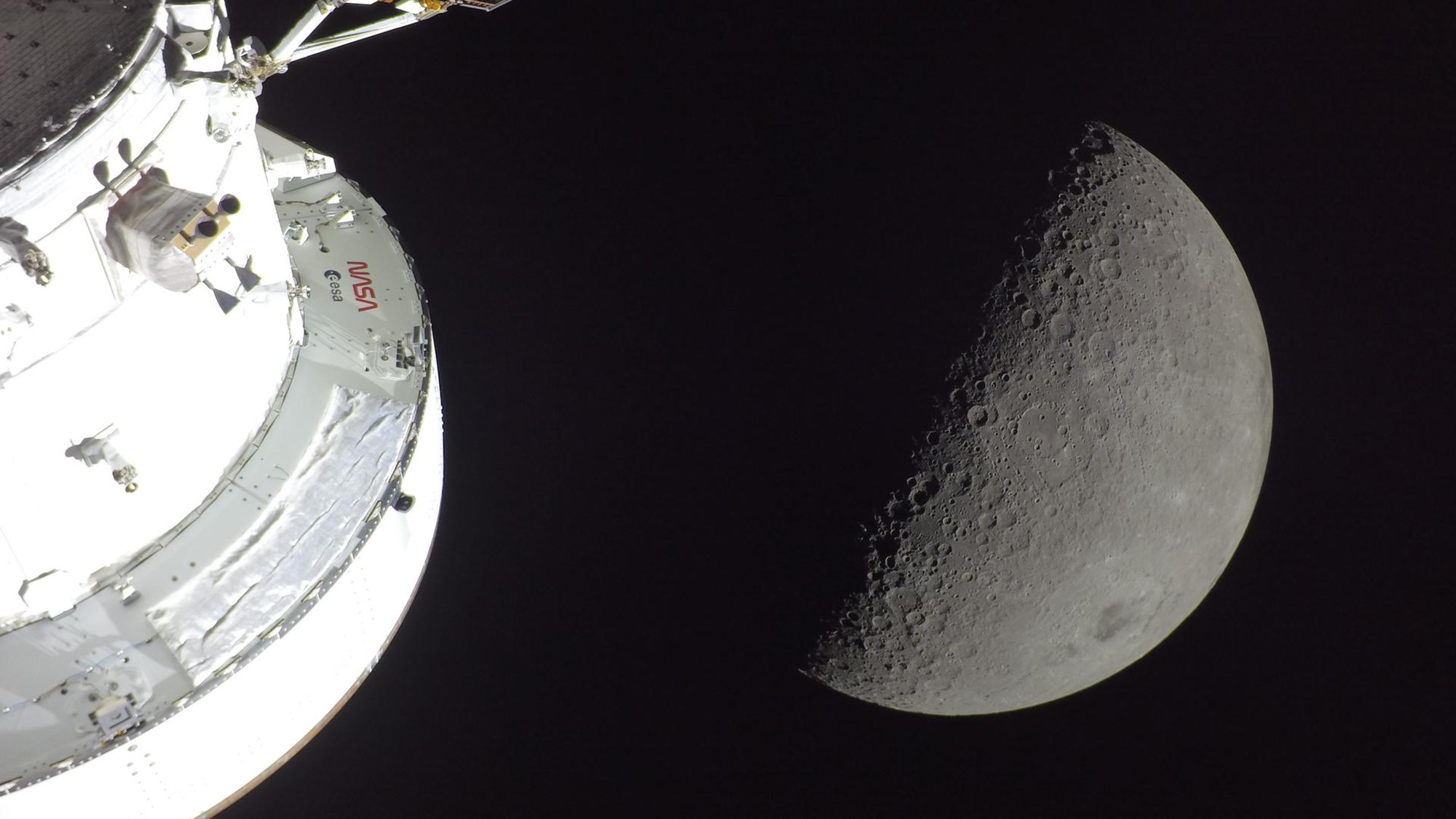 Une vue de la lune grise avec un vaisseau spatial blanc en bas à gauche de l'image.