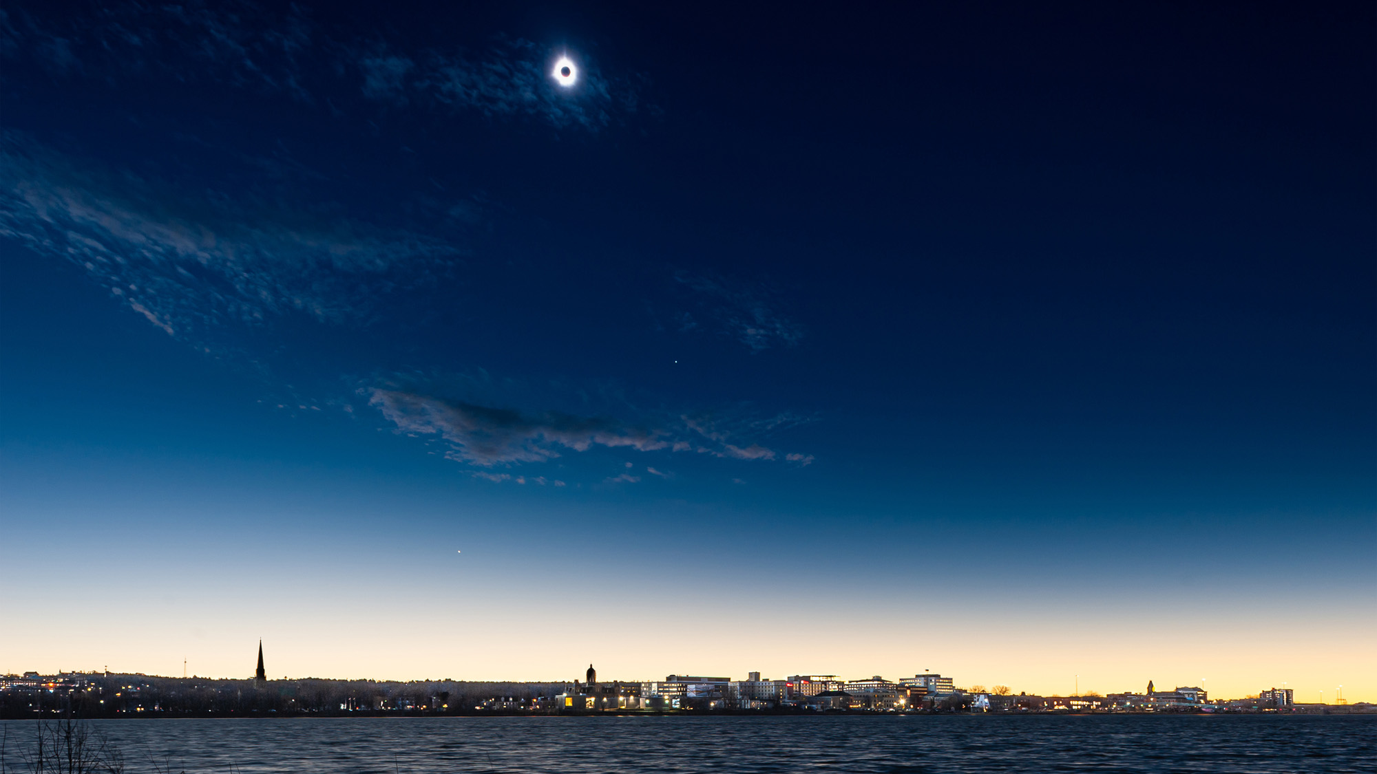 éclipse totale de soleil sur une ville côtière