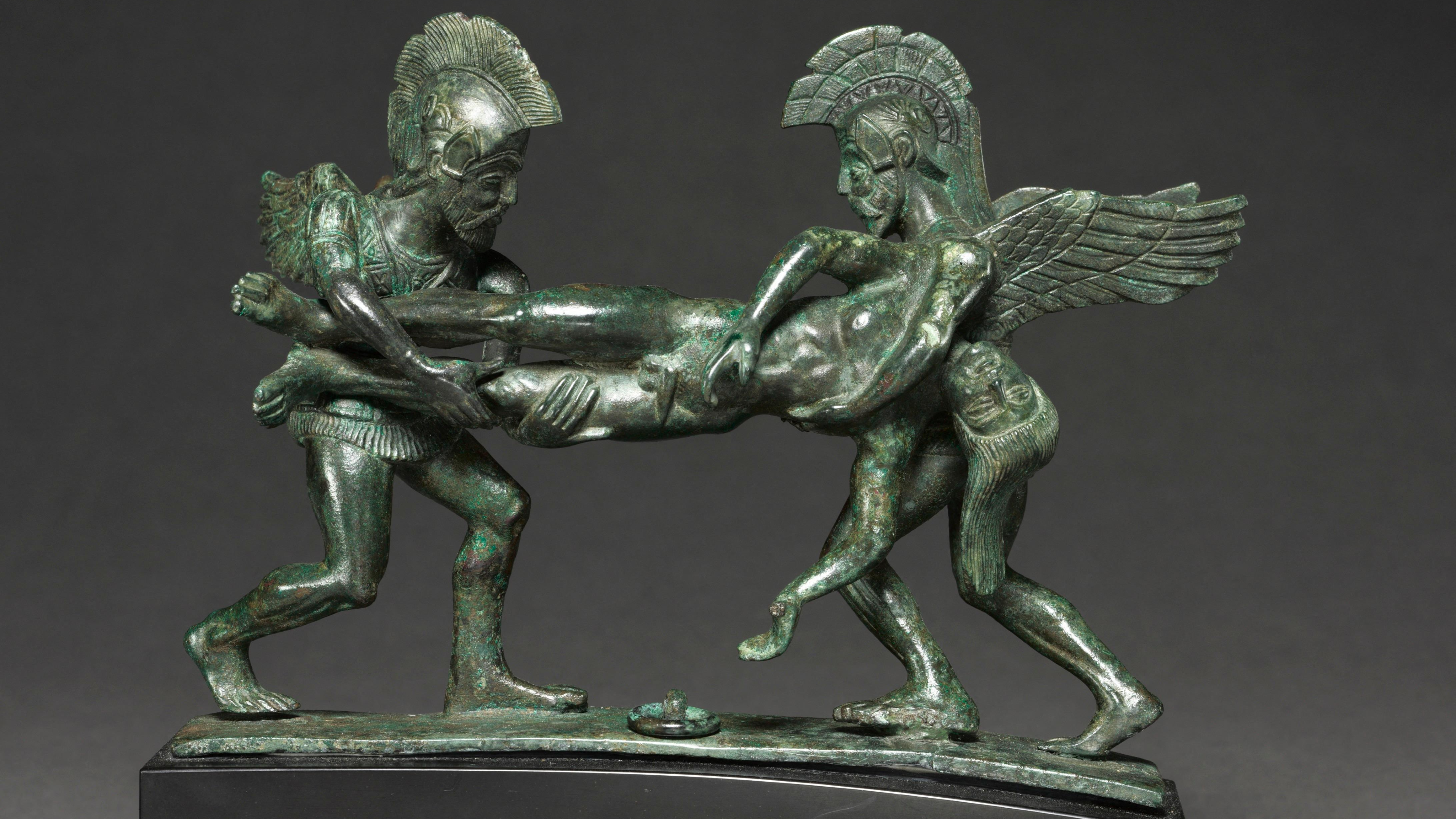 deux personnages casqués en bronze tiennent entre eux un cadavre horizontal