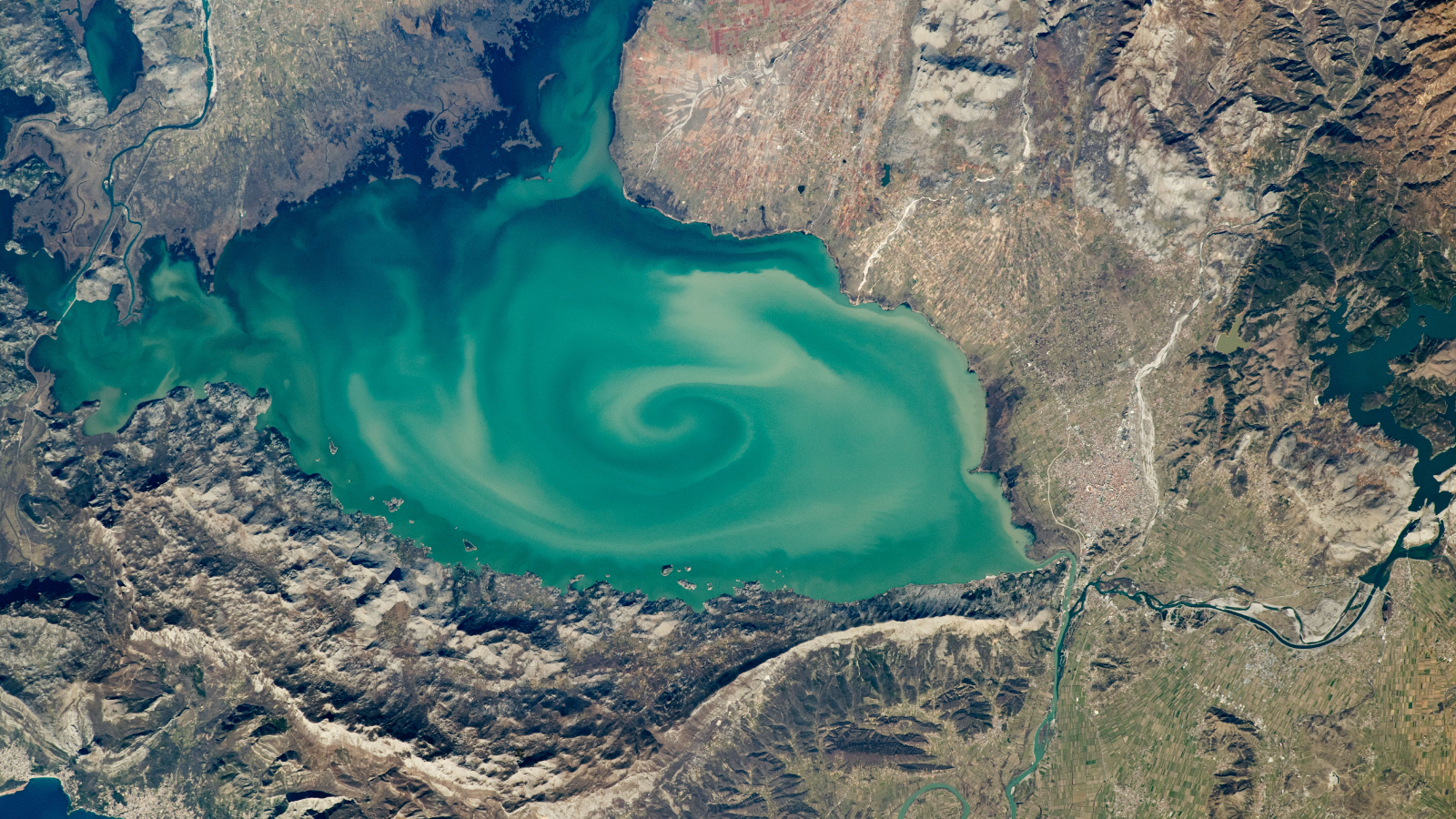 Une photo satellite d'un lac avec un énorme tourbillon vert sur sa surface