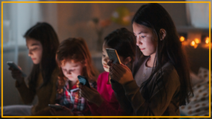 Four children look at their phones in a bedroom
