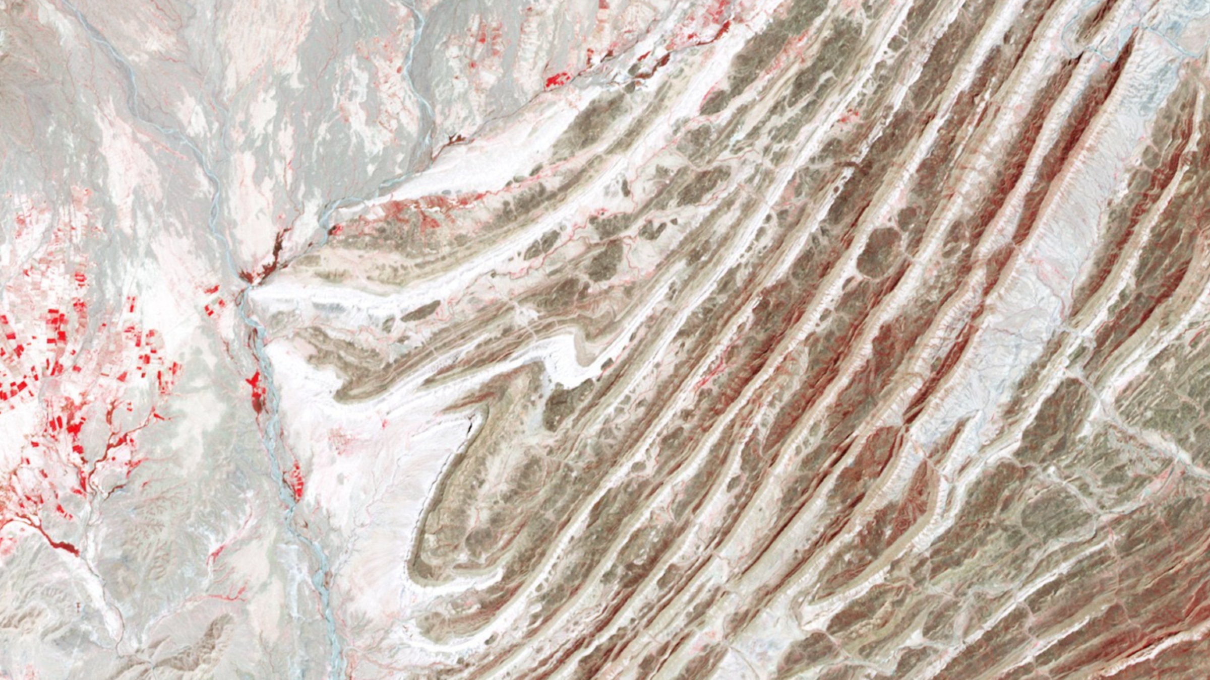 Une photo satellite en fausses couleurs d'une série de plis rocheux alternés à travers le paysage
