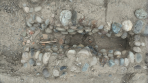 aerial image of a rock-lined channel in the earth with a human skeleton lying at the bottom