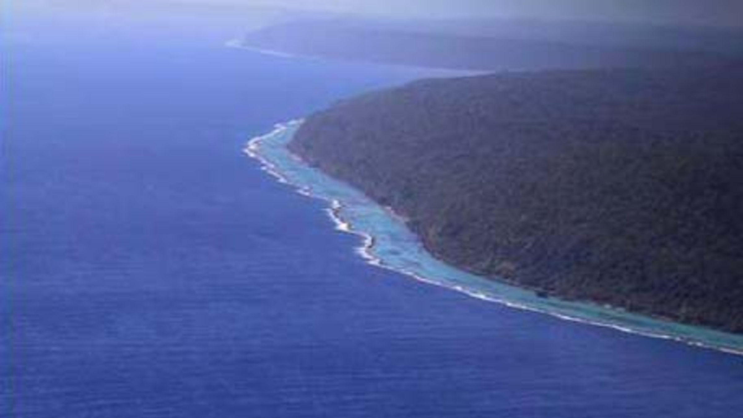 Une photo aérienne de l'île Rennell montrant un récif de corail frangeant longeant son littoral