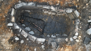 an aerial photograph of an excavated ancient well with a human skeleton at the bottom
