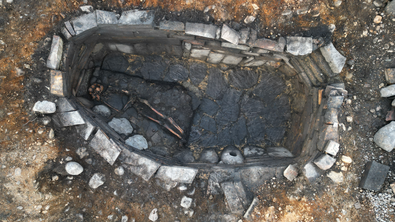 an aerial photograph of an excavated ancient well with a human skeleton at the bottom