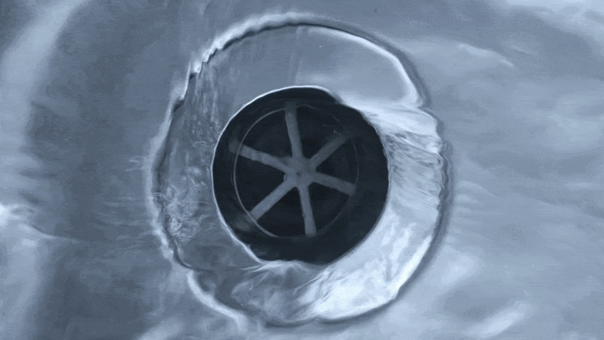 A gif showing water swirling down a metal sink drain