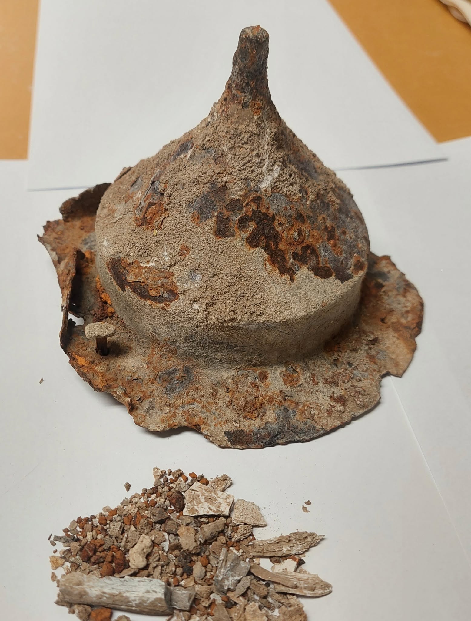 Un récipient en pierre en forme de cône est rempli de cendres grises, posé sur une surface blanche.
