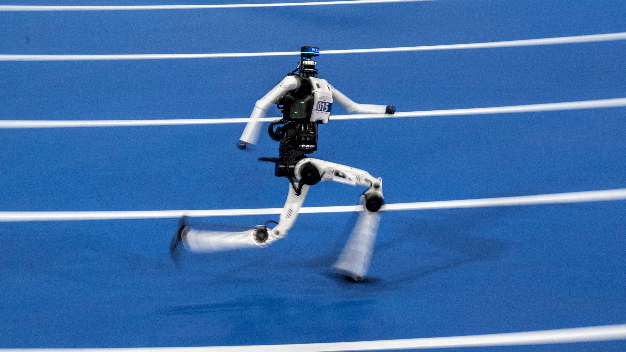 Un robot humanoïde noir et blanc sprinte sur une piste bleue.